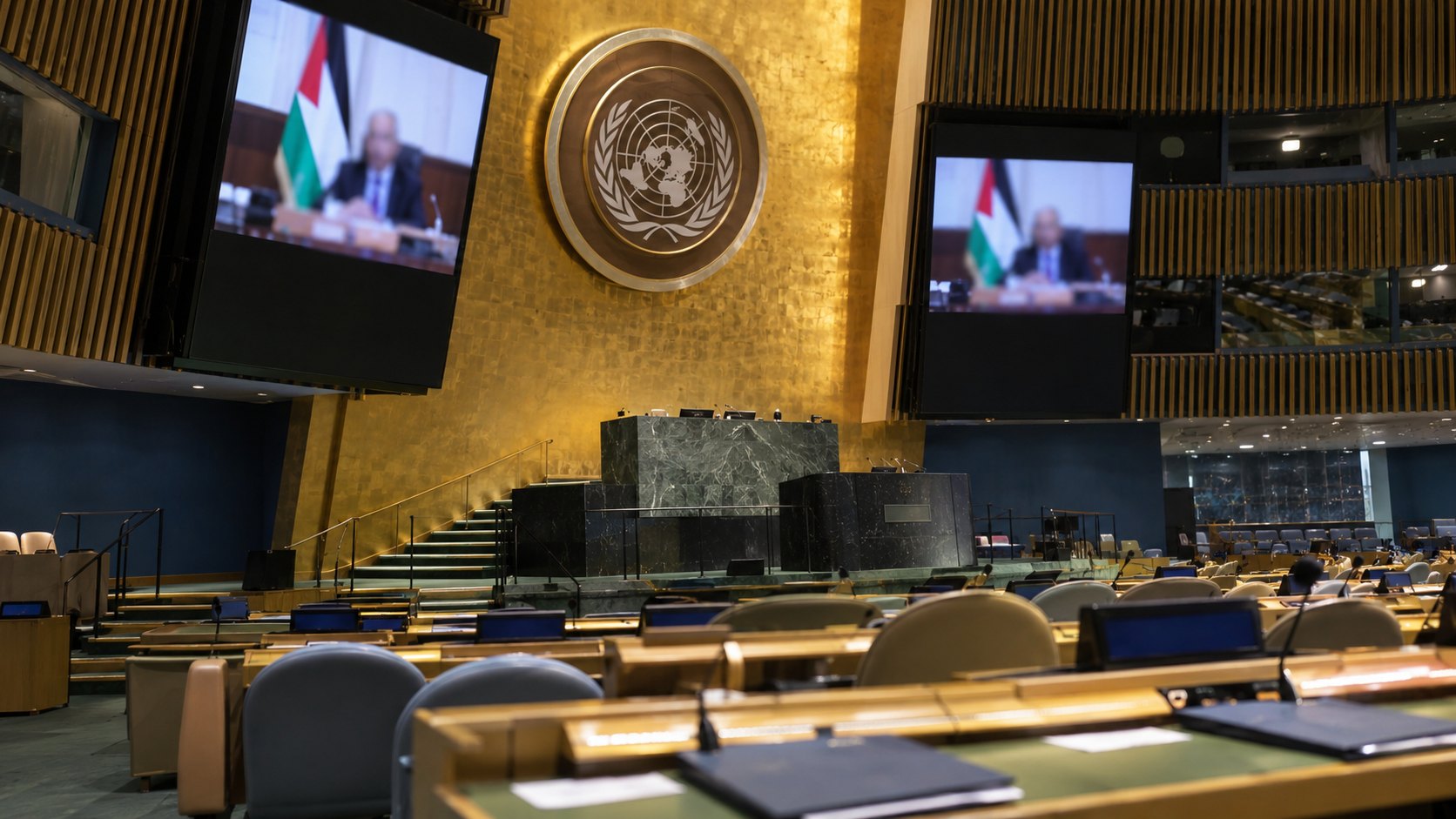 Ilustración editorial generada con IA: el salón de la Asamblea General de la ONU con el estrado vacío y dos pantallas que muestran a un hombre mayor hablando por video junto a una bandera palestina; no es una fotografía del discurso de Abás.