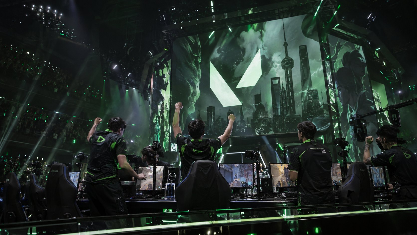 Ilustración editorial generada con IA: jugadores de LOUD con camisetas verdes y negras celebran con los brazos en alto en el escenario de VALORANT Champions en Shanghái, con el logo de VALORANT en la pantalla gigante; no es una fotografía del partido.