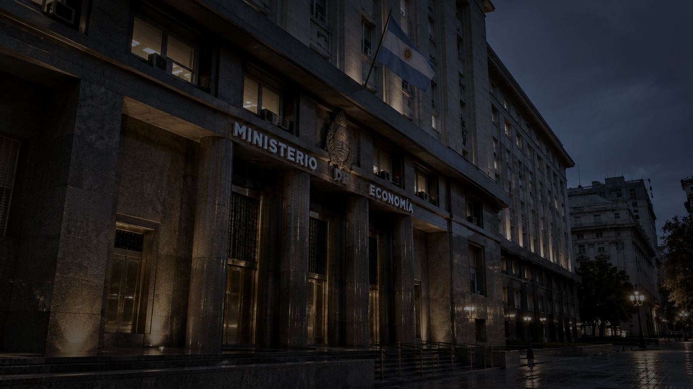 Fachada del Palacio de Hacienda, sede del Ministerio de Economía de Argentina, iluminada al anochecer con la bandera argentina ondeando sobre la entrada