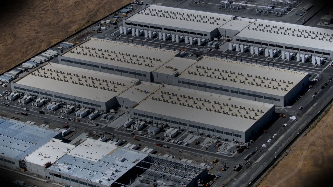 Vista aérea de un campus de centros de datos de Amazon Web Services, con hileras de unidades de refrigeración y equipos de respaldo eléctrico sobre los techos