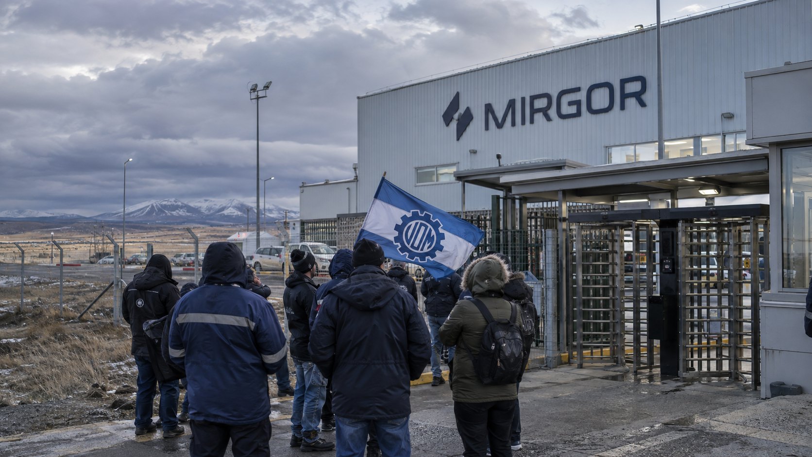 Ilustración editorial generada con IA: operarios con camperas de abrigo, de espaldas, esperan frente a los molinetes cerrados de una planta industrial con el cartel de Mirgor en Río Grande, Tierra del Fuego, bajo un cielo nublado, mientras uno sostiene una bandera de la UOM; composición conceptual, no es una fotografía de la planta ni de los trabajadores despedidos.