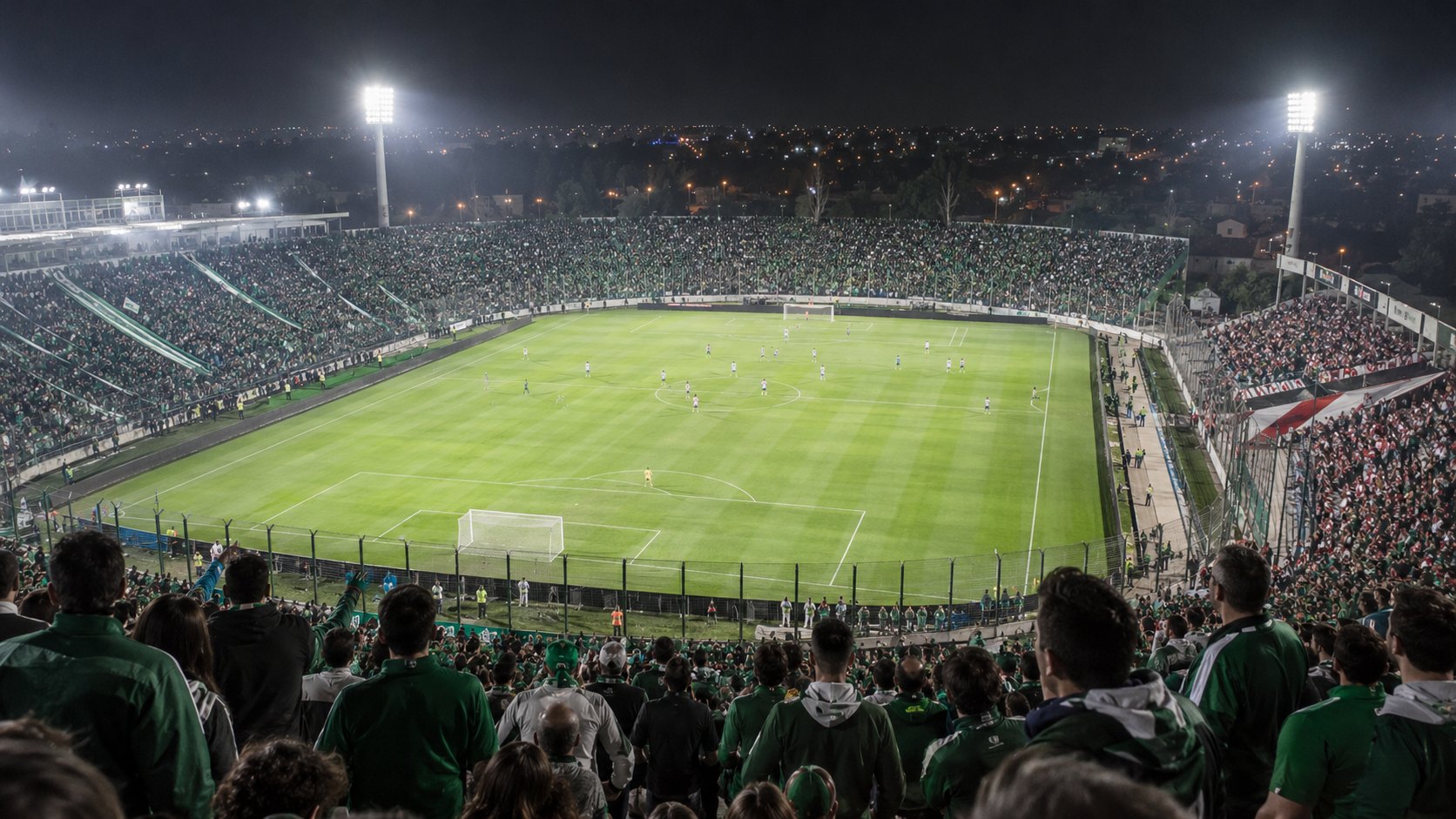Ilustración editorial generada con IA: un estadio de fútbol de noche, con reflectores encendidos y tribunas colmadas de hinchas vestidos de verde, y a un costado una parcialidad visitante de blanco y rojo; no es una fotografía del partido ni representa a personas reales.