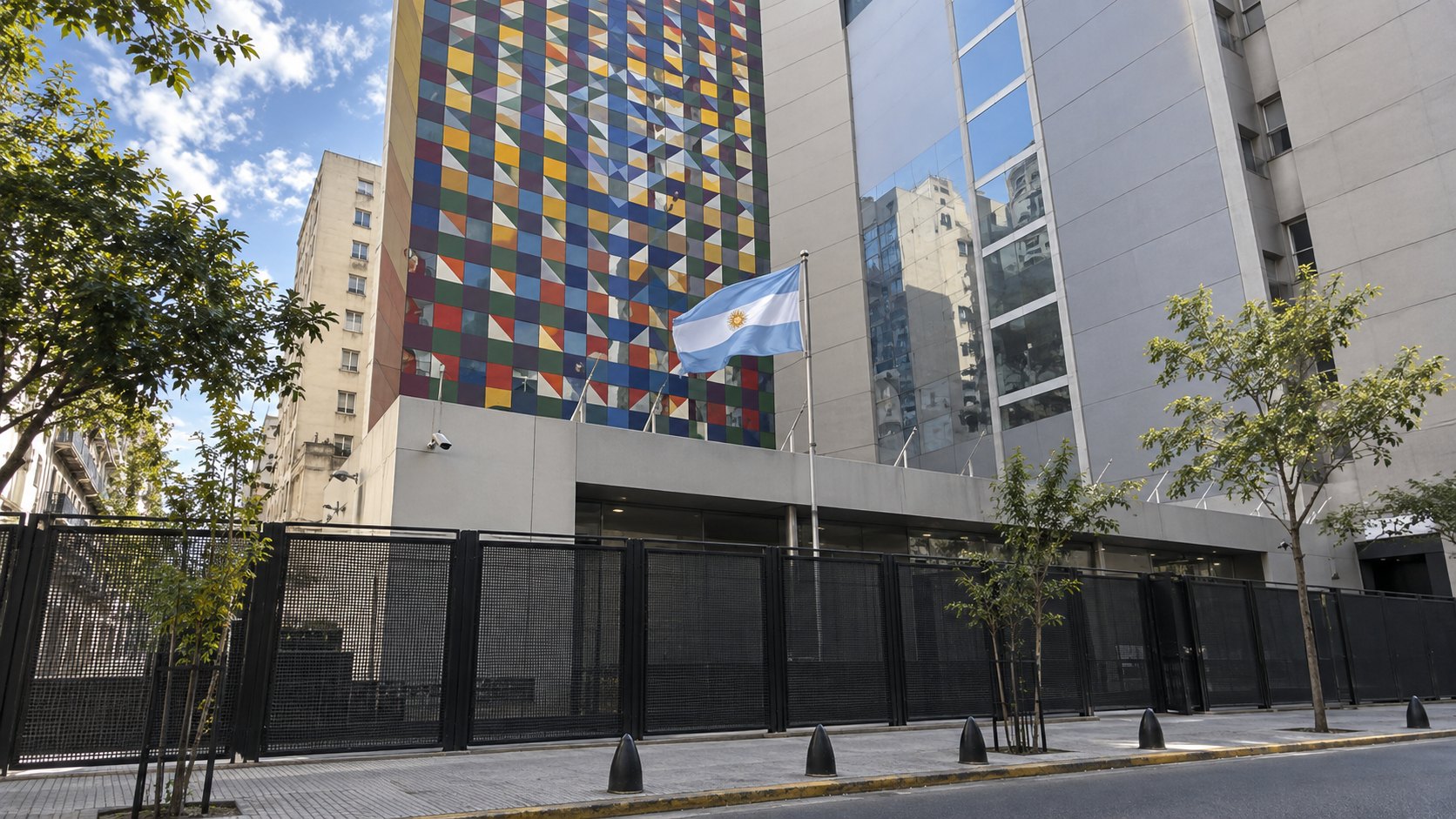 Ilustración editorial generada con IA: la fachada de un edificio en una calle de Buenos Aires con una bandera argentina, rejas de seguridad y bolardos en la vereda; composición conceptual que alude a la memoria de los atentados de 1992 y 1994, no es una fotografía de la sede real de la AMIA.
