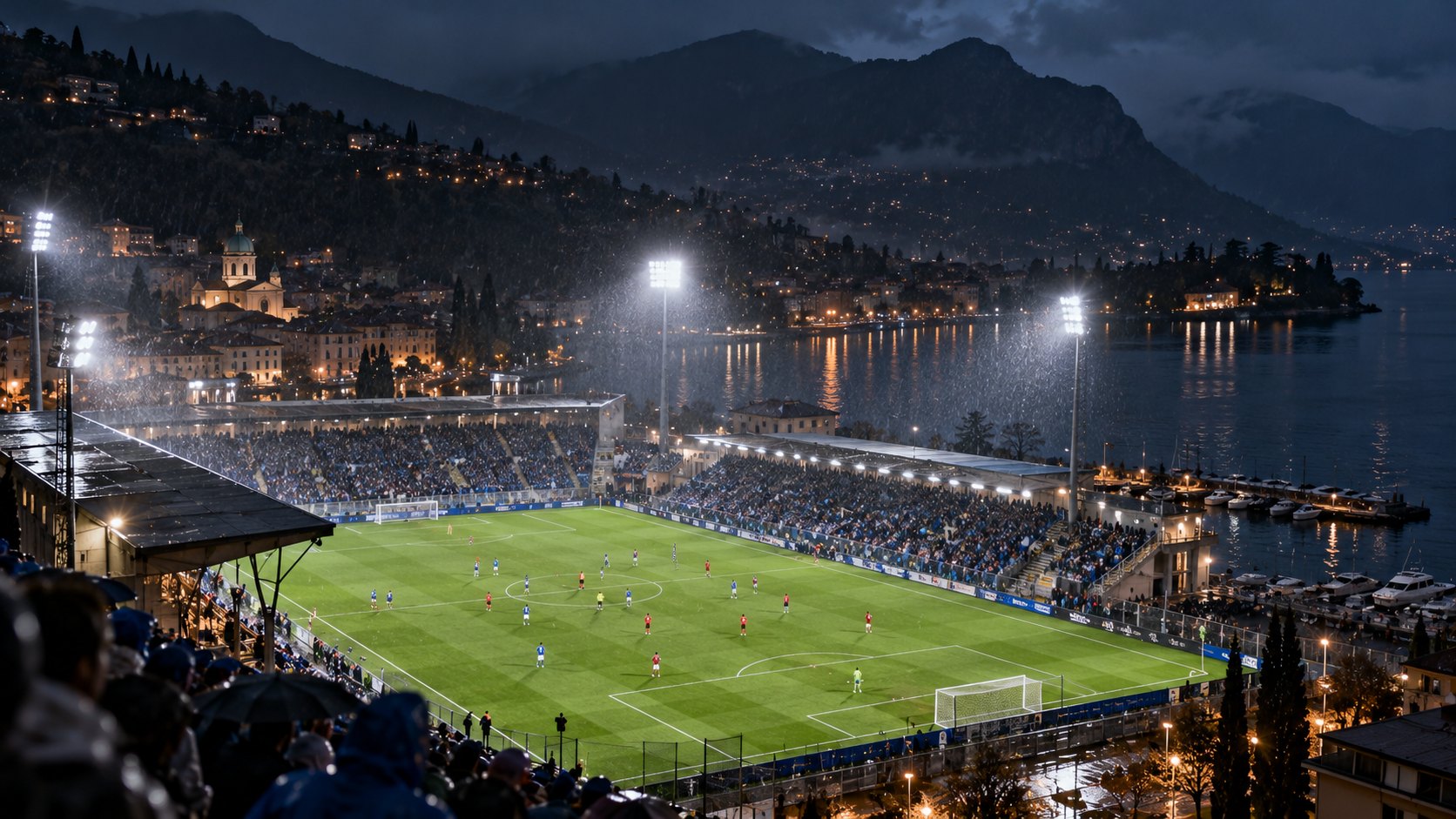Ilustración editorial generada con IA: vista nocturna del estadio Giuseppe Sinigaglia, a orillas del lago de Como, con lluvia, reflectores encendidos y un partido en juego; composición conceptual, no es una fotografía del partido.