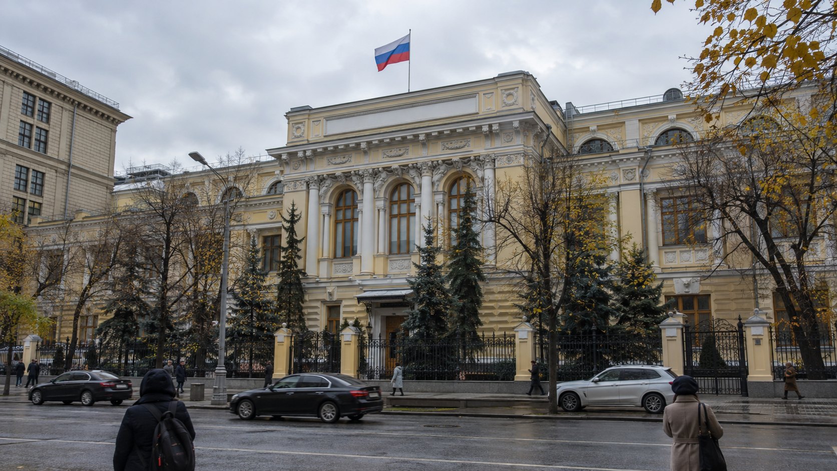 Ilustración editorial generada con IA: la fachada neoclásica del Banco Central de Rusia en la calle Neglinnaya de Moscú, con la bandera rusa en el techo, árboles otoñales, autos y peatones de espaldas bajo un cielo gris; composición conceptual, no es una fotografía del día.